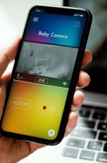Eine Hand hält ein Smartphone, auf dem eine Babyphon-App geöffnet ist.
