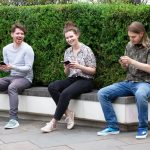 Drei Personen sitzen auf einer Bank und halten das Samsung Galaxy Z Fold2 und Z Flip in den Händen.