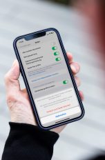 Eine Person hält ein iPhone in den Händen. Darauf sind die Einstellungen zu sehen, in denen sich der Browser-Cache leeren lässt.